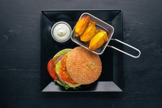 Foto hamburguesa y patatas con salsa sobre un fondo de madera vista superior espacio libre para el texto