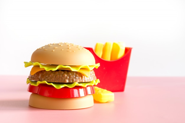 Hamburguesa de plástico, ensalada, tomate, papas fritas con rosa.