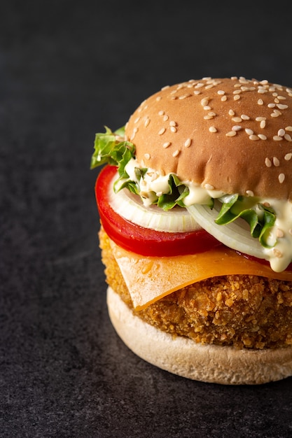 Hamburguesa de pollo crujiente en mesa de pizarra negra