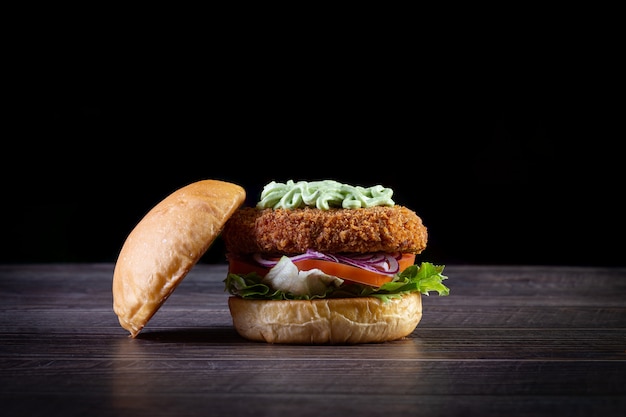 Hamburguesa de pollo con lechuga, tomate, cebolla morada y mayonesa hecha a mano sobre la mesa de madera. Delicioso.