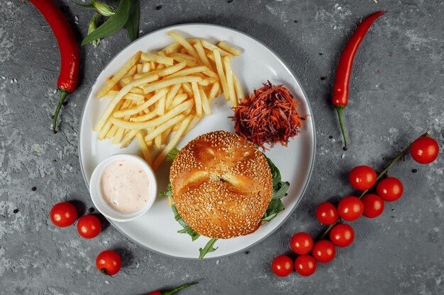 Hamburguesa de pollo con papas fritas y ensalada en una vieja mesa de hormigón