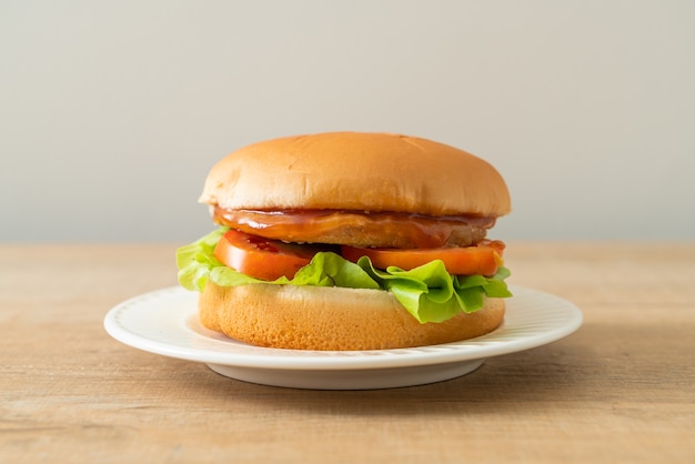 Hamburguesa de pollo con salsa en la placa blanca.