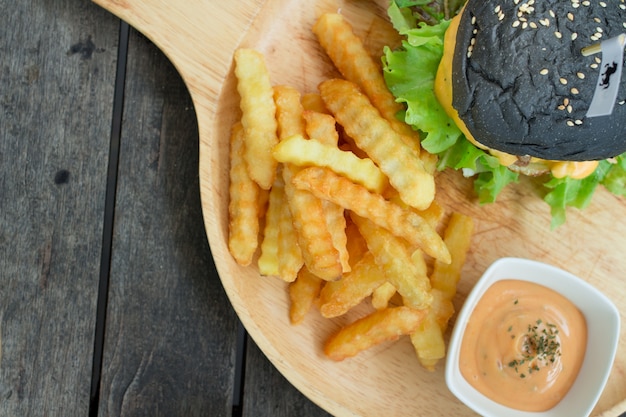 hamburguesa de queso de carbón en placa de madera con francés fresco frito