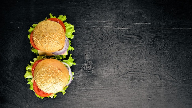 Hamburguesa con queso, carne, tomates, cebollas y hierbas Sobre fondo de madera Vista superior Espacio libre