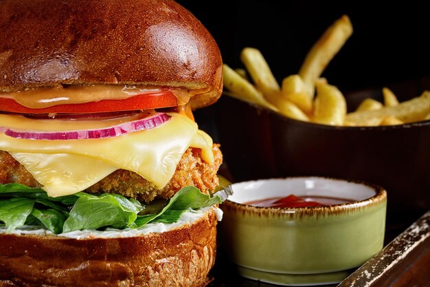 hamburguesa con queso de carne y verduras patatas fritas y salsa sobre un fondo negro