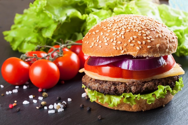 Hamburguesa con queso casera sobre superficie de pizarra negra