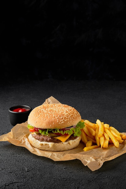 Hamburguesa con queso clásica y papas fritas en el menú de parrilla de barbacoa de fondo negro