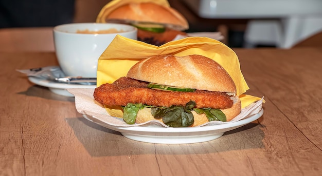 Hamburguesa con queso de ensalada fresca y chuleta y una taza de café en una mesa de madera