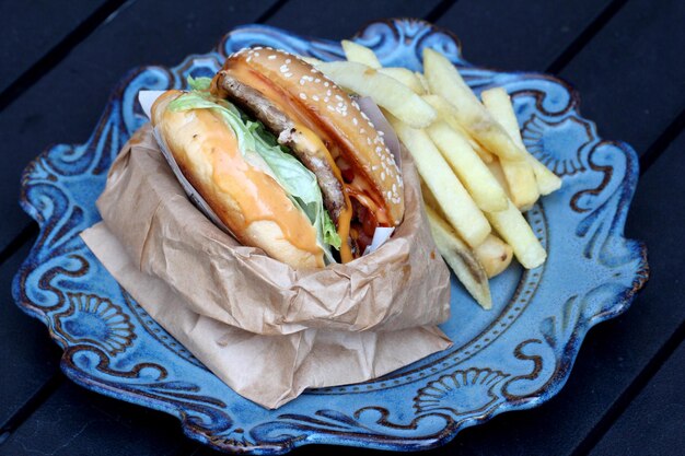 Foto hamburguesa con queso y patatas fritas en un plato azul