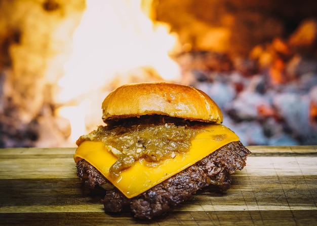 Una hamburguesa con queso con salsa barbacoa se asienta sobre una tabla de madera frente a una chimenea.