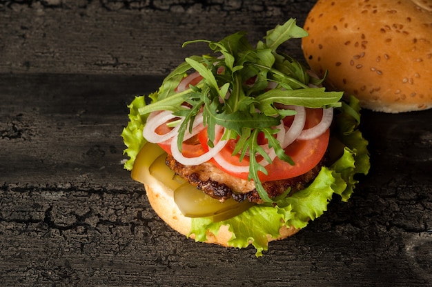 Hamburguesa con queso sobre una vieja superficie de madera de color oscuro amburger con carne y tomate en una vieja madera