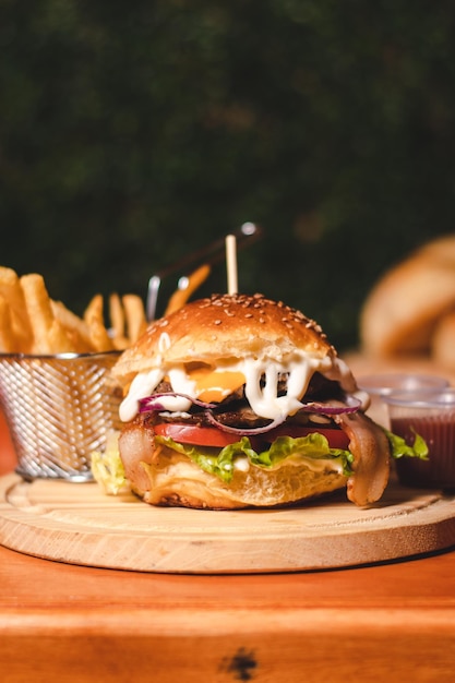 Hamburguesa rellena de queso derretido y condimentos con papas fritas en la parte inferior sobre una mesa de madera