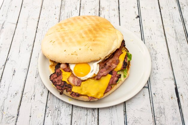 Hamburguesa salvaje con las típicas tiras de huevo frito y tiras de bacon y queso cheddar y mucha lechuga