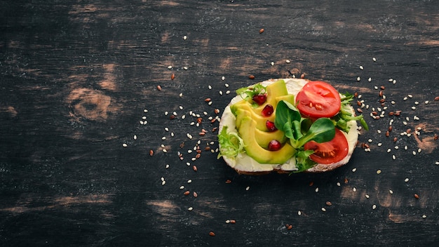 Hamburguesa sándwich de aguacate tomates cherry y hojas de lechuga Sobre un fondo de madera Vista superior Espacio de copia