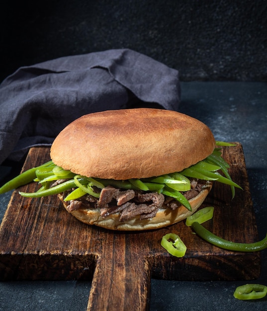 Foto hamburguesa sándwich chilena latinoamericana chacarero con rodajas de carne de primera calidad y judías verdes sobre fondo negro