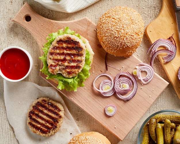 Hamburguesa sobre tabla de madera con cebolla y tomate