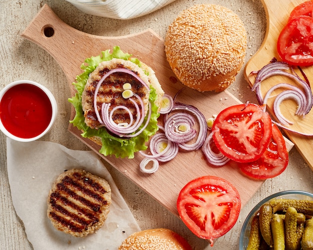 Hamburguesa sobre tabla de madera con cebolla y tomate