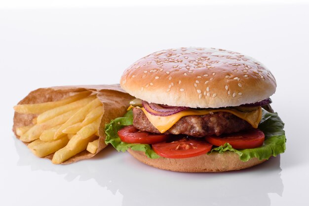 Hamburguesa de ternera artesanal y papas fritas sobre un fondo blanco.