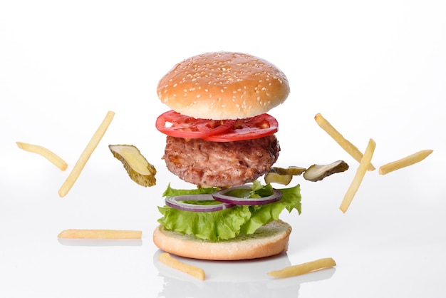 Hamburguesa de ternera artesanal y papas fritas sobre un fondo blanco.