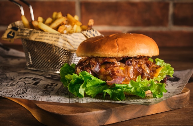 Hamburguesa con ternera y cebolla caramelizada sobre una tabla de madera. Hamburguesa con cebolla y ternera.