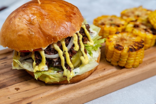 hamburguesa de ternera jugosa en una tabla de madera con maíz frito