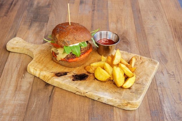 Hamburguesa de ternera con patatas asadas sobre fondo de madera.