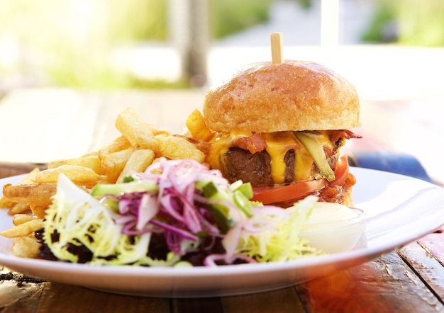 Hamburguesa con tocino y queso y papas fritas con ensalada saludable