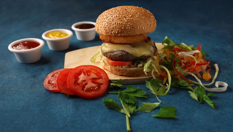una hamburguesa con un tomate en ella y una rebanada de tomate en el tablero