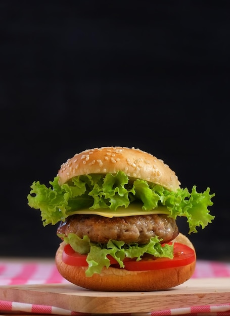 Una hamburguesa con tomate y lechuga encima.