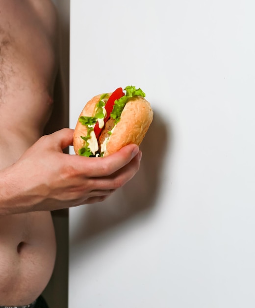 Hamburguesa con tomates y una chuleta en manos masculinas primer plano contra el fondo de un refrigerador