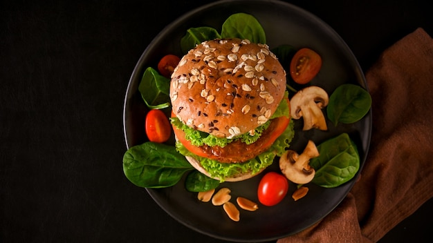 Hamburguesa vegana con carne vegana de pan integral y verduras orgánicas frescas sobre fondo negro