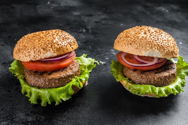 Hamburguesa vegana con chuletas sin carne a base de plantas, empanadas, tomate y cebolla. Fondo negro. Vista superior.