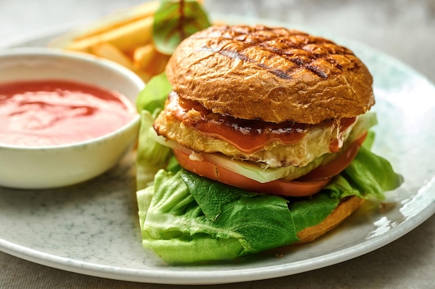 Hamburguesa con verduras y pollo en un plato. Primer plano, enfoque selectivo. Una guarnición de papas fritas