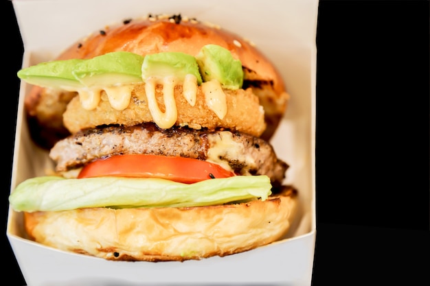 Una hamburguesa de vista lateral que muestra sus capas en una caja blanca y fondo negro