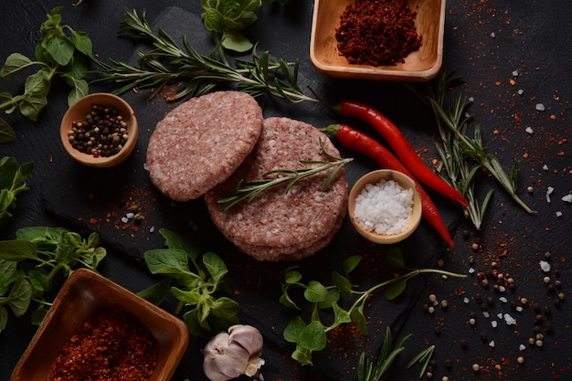 Hamburguesas de carne cruda con hierbas y especias. Chuletas de hamburguesa cruda sobre un fondo de hormigón