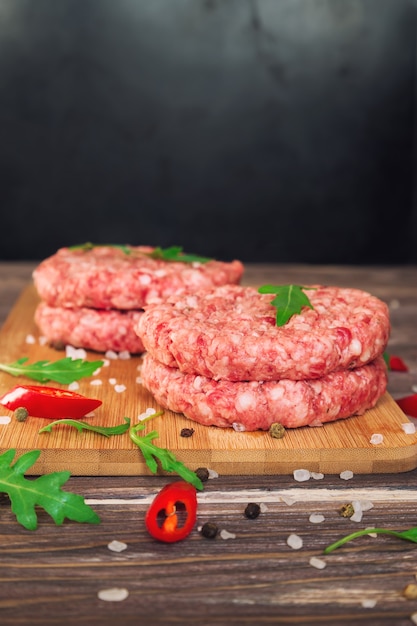 Hamburguesas de carne molida cruda con ají y rúcula en la mesa de madera rústica