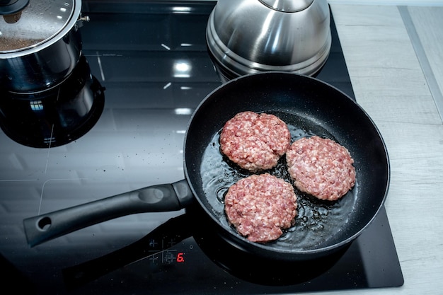 Foto hamburguesas de carne o empanada en forma de chuleta frita en aceite en una sartén en un plato negro de cerca versión rusa o polaca de chuletas kotlety vista superior lay plano
