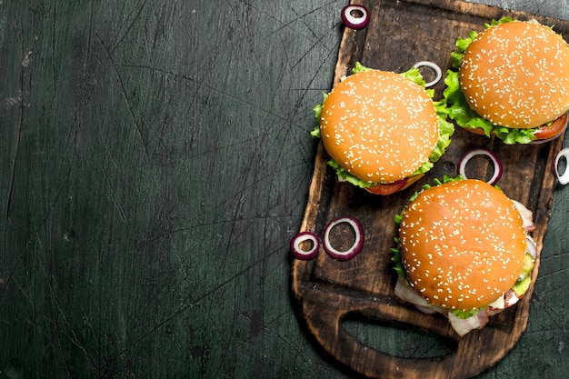 Hamburguesas con carne, verduras y cebollas dulces en una vieja placa sobre un fondo rústico