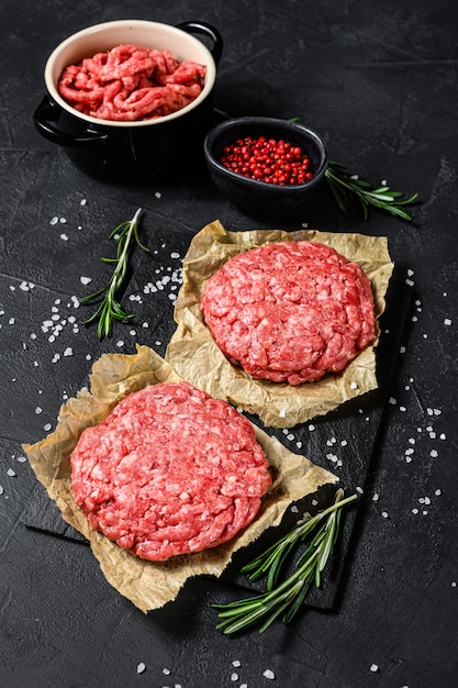 Hamburguesas caseras de carne cruda picada. Granja de carne orgánica. Fondo negro. Vista superior