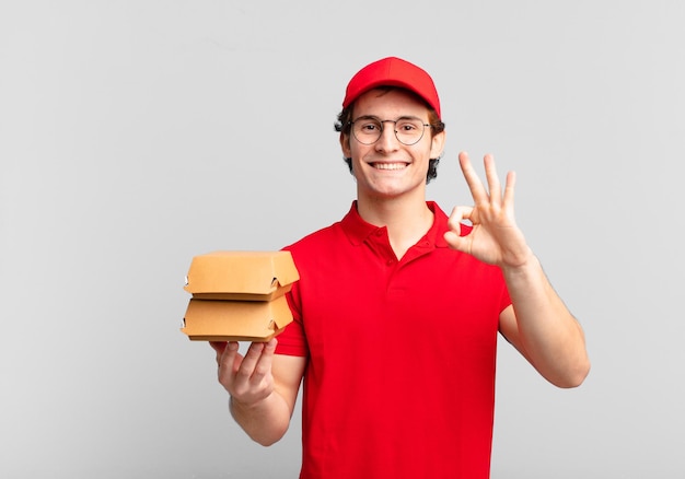 Las hamburguesas entregan al niño sintiéndose feliz, relajado y satisfecho, mostrando aprobación con un gesto aceptable, sonriendo