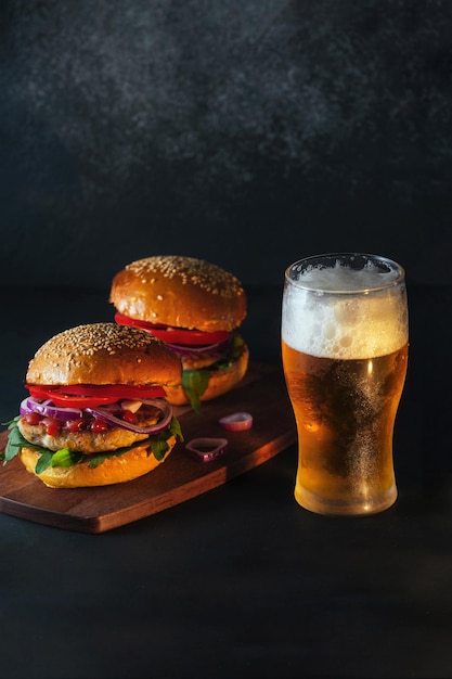 Hamburguesas listas y apetitosas con un vaso de cerveza fría en un fondo oscuro