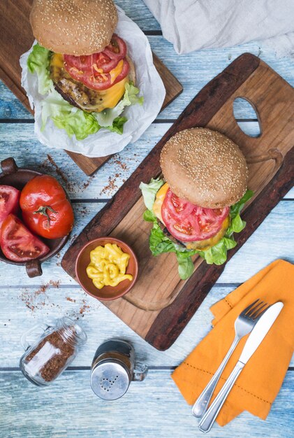 Hamburguesas en una mesa, mostaza y tomate.