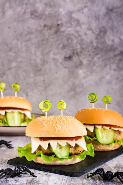 Hamburguesas monstruosas para el menú de halloween en pizarra y arañas Comida casera creativa Vista vertical