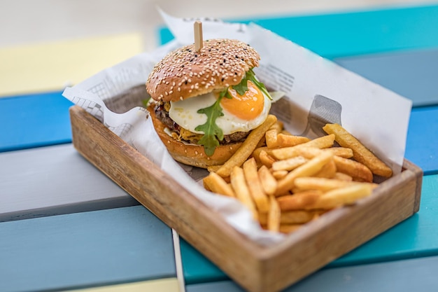 Hamburguesas y papas fritas en la bandeja de madera. Hamburguesa gourmet de ternera con lechuga y queso frito