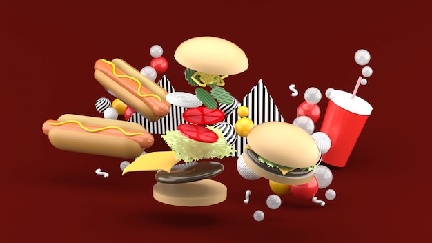 Hamburguesas, perritos calientes y refrescos entre bolas de colores en rojo. Representación 3d