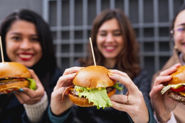 Hamburguesas de primer plano. Sonriendo hembras irreconocibles en el fondo.