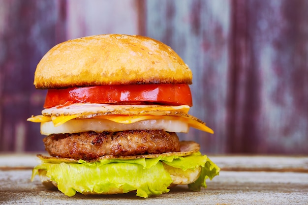 Hamburguesas con queso en empanadas de carne e ingredientes frescos para ensaladas servidos en una mesa de madera rústica