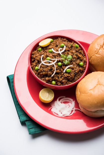 Hammel Kheema Pav ODER indisches würziges Hackfleisch serviert mit Brot ODER Kulcha, garniert mit grünen Erbsen. Stimmungsvoller Hintergrund. Selektiver Fokus