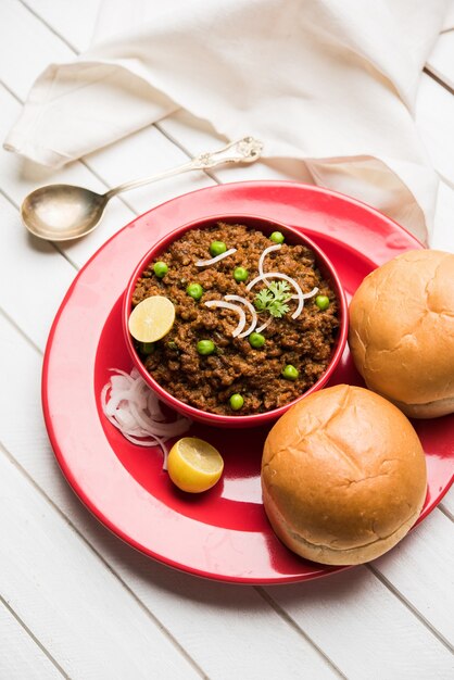 Hammel Kheema Pav ODER indisches würziges Hackfleisch serviert mit Brot ODER Kulcha, garniert mit grünen Erbsen. Stimmungsvoller Hintergrund. Selektiver Fokus