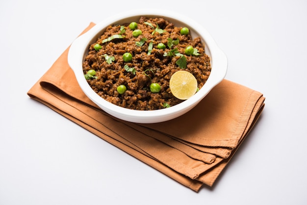 Hammel Kheema Pav ODER indisches würziges Hackfleisch serviert mit Brot ODER Kulcha, garniert mit grünen Erbsen. Stimmungsvoller Hintergrund. Selektiver Fokus